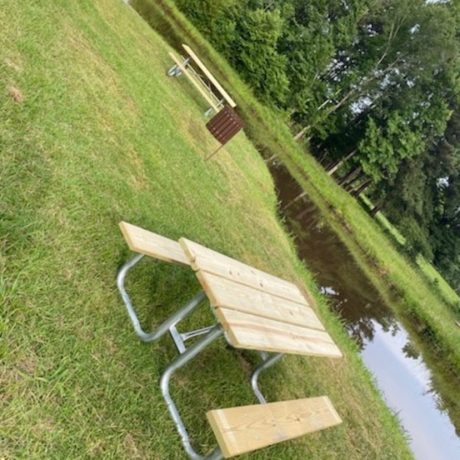 A serene fishing pond with lush greenery around it, reflecting the peaceful environment of Bedrock RV Park in Longview, Texas. 